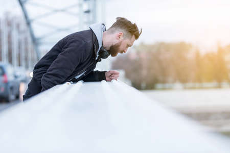 A handsome young hipster man looking at the river from the bridge.の写真素材