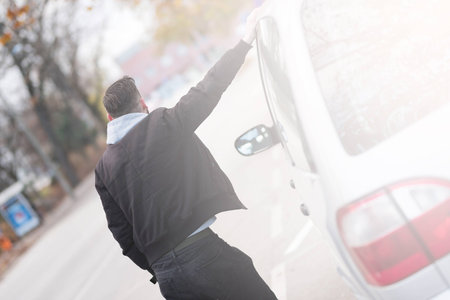 Back view of a hipster man standing next to his car and waiting.の写真素材
