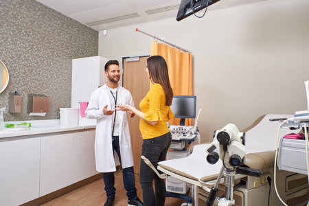A beautiful young pregnant woman consulting with the handsome doctor in clinic.の写真素材