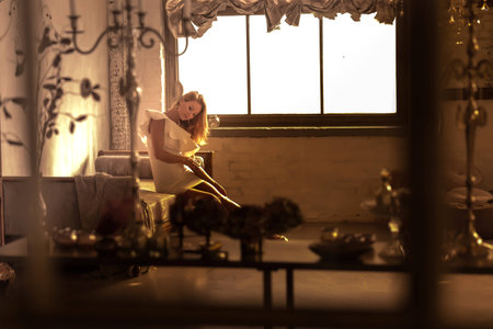 Portrait of a beautiful young woman sitting on a antique Sofa at night.の写真素材
