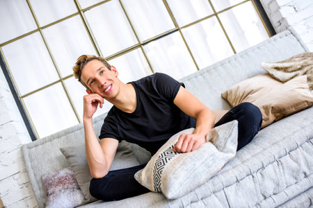 A young handsome man relaxing on the sofa in a loft style apartmの写真素材