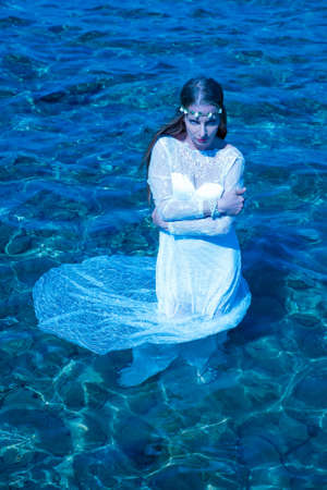 Young woman standing in the ocean at night