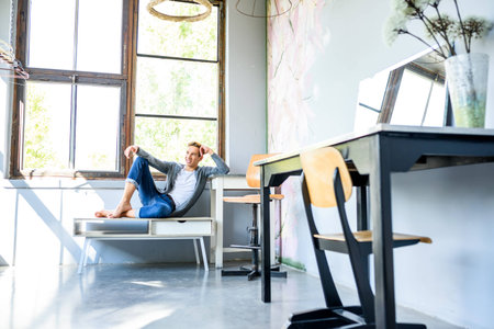 A young handsome male Dancer resting in a modern Loft Apartmentの写真素材
