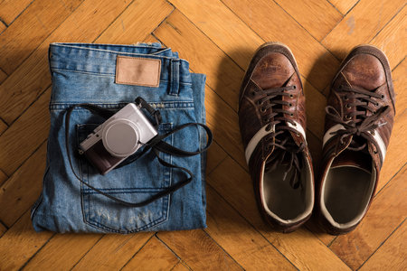 Blue jeans, brown shoes, and a cameraの写真素材