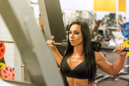 A woman performing weight lifting exercises in the Gymの写真素材