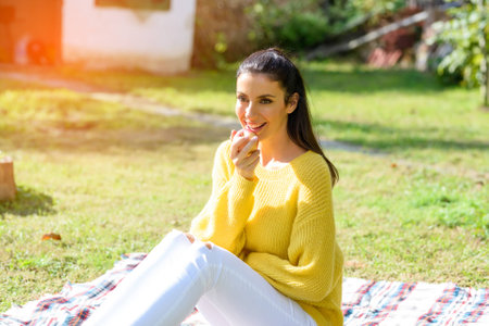 A beautiful woman eating a Apple in the Garden in Autumnの写真素材