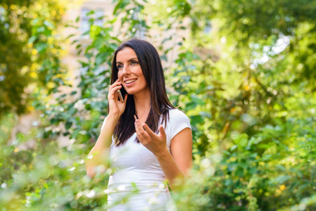 A cheerful young woman in a Park talking on a phoneの写真素材