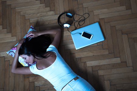 Beautiful woman laying on the floor with a laptop, smartphone, cの写真素材