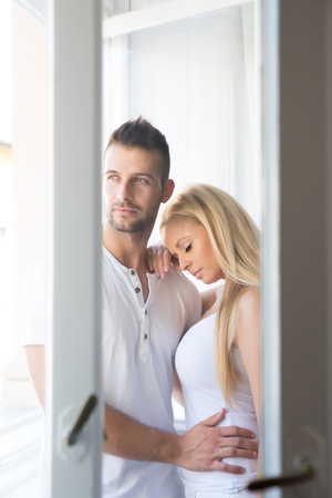 Beautiful young couple standing at the windowの写真素材