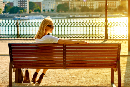 Young woman siting on a bench on the riversideの写真素材