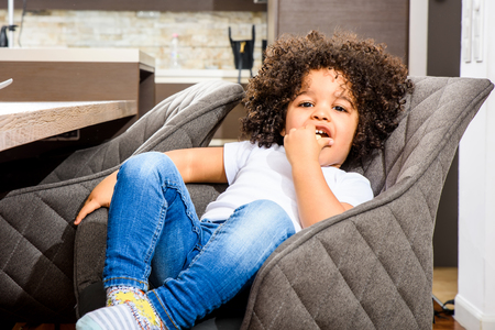 Portrait of a young afro child sitting at the kitchenの写真素材