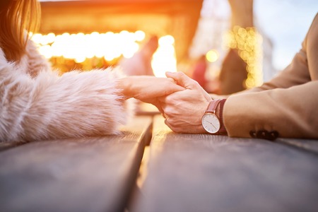 Close view of a couple sitting and holding hands in a christmas market.の写真素材