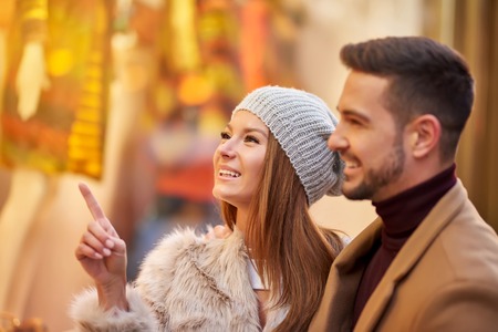 A beautiful young couple smiling and checking the gifts in a christmas market.の写真素材