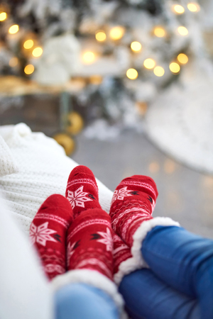 A couple laying on the sofa and wearing red christmas themed socks.の写真素材