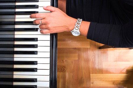 Hands of an elegant classical musician woman playing on piano.