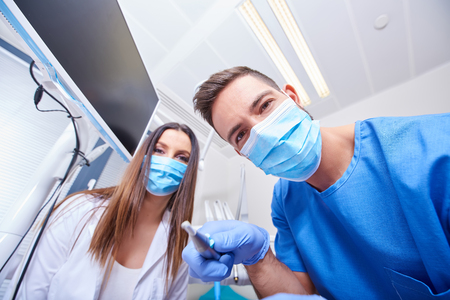 A handsome dentist and a beautiful assistant at a treatment, from the perspective of the patient.の写真素材
