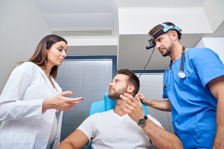 A doctor and his assistant consulting with the patient in the hospital room.