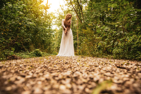 Dark mood photo of a woman while standing and posing in the forest.の写真素材