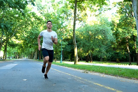 A handsome young man jogging in a park