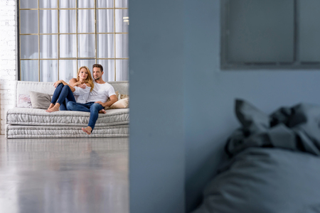 A beautiful young couple sitting on the sofa and cuddling.の写真素材
