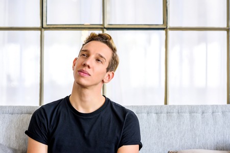 A young handsome man relaxing on the sofa in a loft style apartm