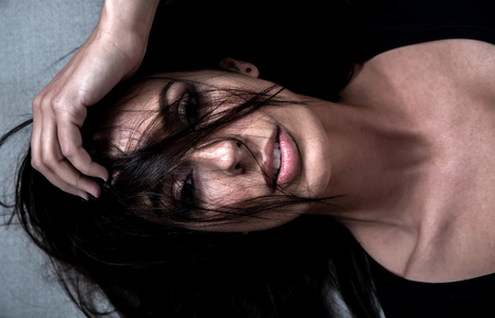 Dark mood sensual portrait of a beautiful woman while lying on a sofa.の写真素材