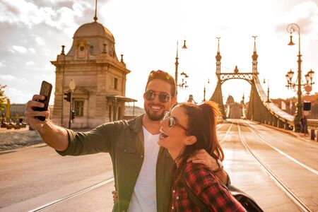 A happy couple taking a selfie in front of the famous liberty bridge during summer in Budapest in Hungary..の写真素材