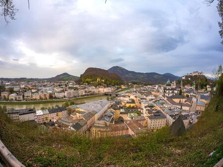 SALZBURG, AUSTRIA - CIRCA APRIL 2018: Panorama view on the historic architecture of the city as traffic passes by at the riverbank and on the bridges of the river Salzach in the downtown during dusk circa April 2018 in Salzburg, Austria.のeditorial素材