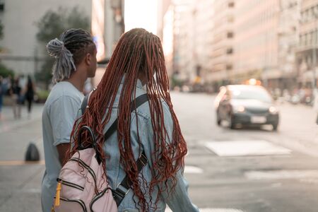 A black couple standing at a road in the city waiting to cross.の写真素材