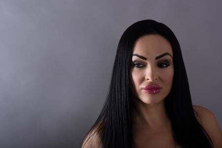 Portrait of a beautiful mature woman on a grey background.