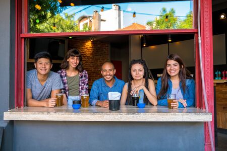 A group of friends conversating and sitting together in a bar or pub while having beer.