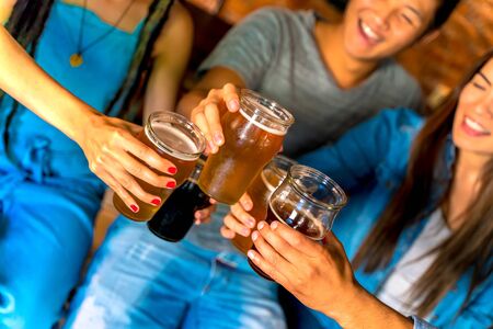A happy group of international friends toasting in a pub, bar or restaurant with draft beers.