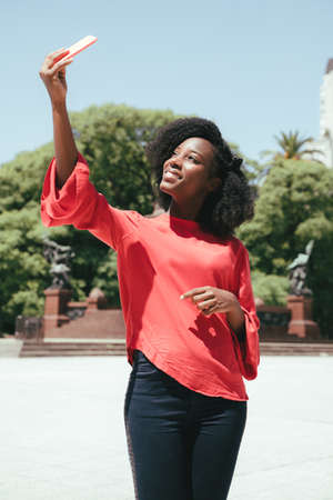 A black young woman taking a selfie in the city.