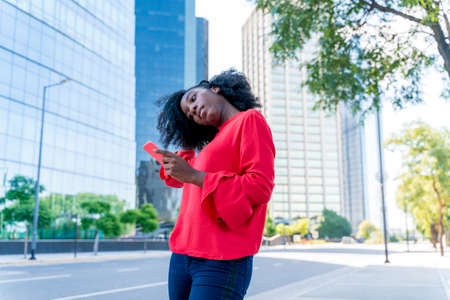 A beautiful black woman using her phone in a big city.の写真素材