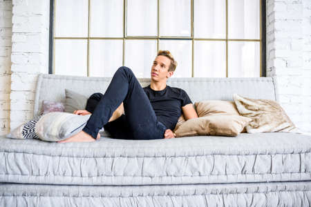 A young handsome man relaxing on the sofa in a loft style apartm