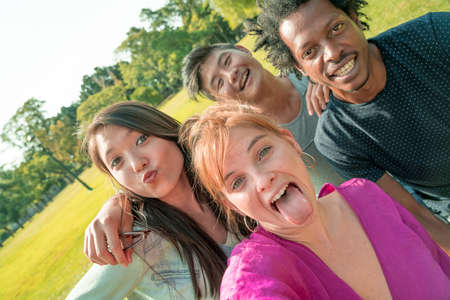 Seflie photo of a happy group of multiethnic friends outdoors on a sunny day in a park.の写真素材