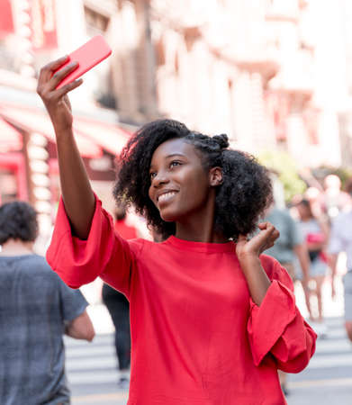 A young black adult woman taking selfies with her phone in the city.の写真素材