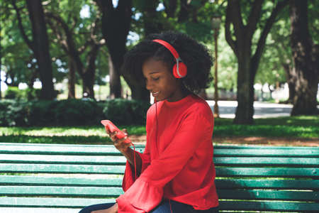 A young black woman listening to music on her headphones in a park.の写真素材