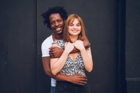 Multi-ethnic couple hugging front of a grey backgroundの写真素材