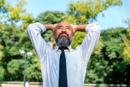 Asian businessman relaxing in a city park during the day.の写真素材