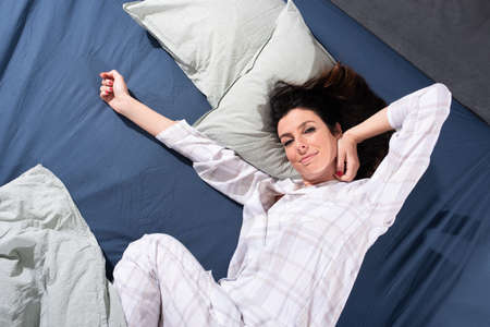 Happy young woman stretching in bed in the morning.