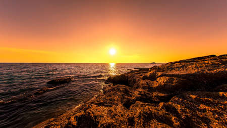 Sunset on the rocks of Surin beach, Phuket, Thailandの写真素材