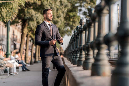 A businessman standing next to a tramlineの写真素材
