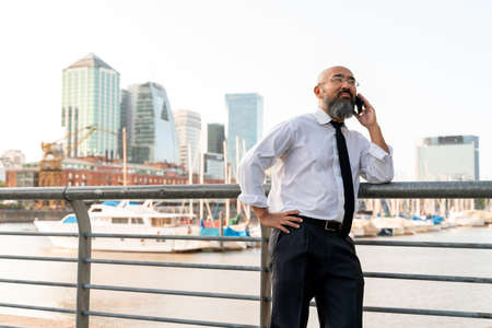 Asian businessman talking on the phone at the harbour in a big city.