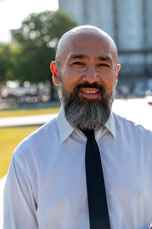Happy Asian businessman standing on the street wearing white shirt.