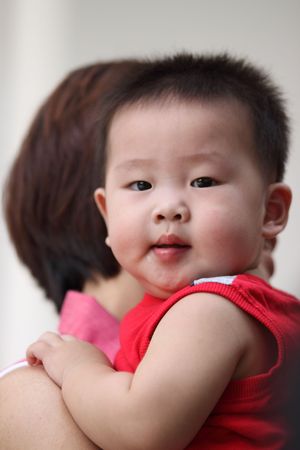 An Asian toddler in his mother's armsの写真素材