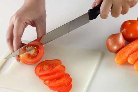 A woman slicing tomatoes on a cutting board to be cooked