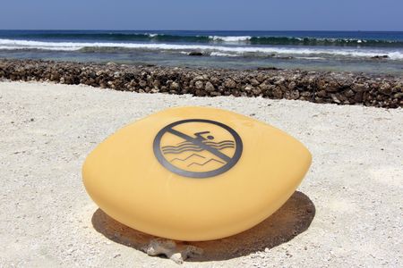 A contemporary 'no swimming' rock sign on the beach of Kandooma Resort, Maldivesの写真素材