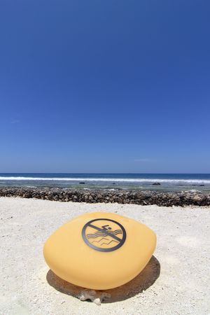 A contemporary 'no swimming' rock sign on the beach of Kandooma Resort, Maldivesの写真素材