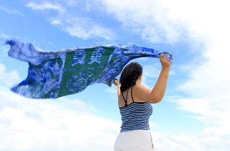 An Asian woman holding a blue shawl in the windの写真素材